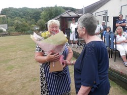 Pauline presents Janine with flowers for her hard work