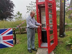 Postling phone kiosk restoration AFTER. Grand opening by parish council chairman Frank Hobbs, 5 June 2022