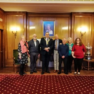 A group photo of us all under a photo of Her Majesty, Queen Elizabeth II. L to R: Bernie, Trevor, Lord Mayor, Charlie, Richard, June and Vanessa.
