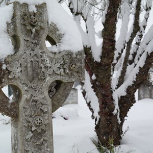 Black and white photo of cross with snow in old section