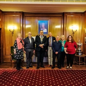 A group photo of us all under a photo of Her Majesty, Queen Elizabeth II. L to R: Bernie, Trevor, Lord Mayor, Charlie, Richard, June and Vanessa.