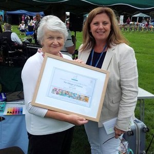 Ros Blackman receiving the award on behalf of the village from the CEO of Sebastian's Trust