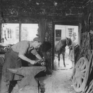 Dick Newman working in the forge making horse shoes before breakfast.