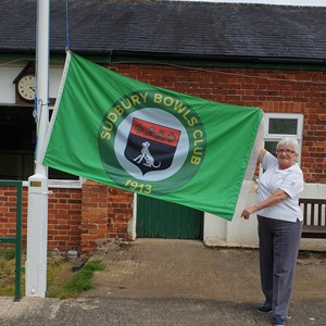 Club President Mrs Rachel Bonsor holding the new club flag, which she kindly donated to the club. An engraved brass plaque in recognition has been attached to the flag pole support.
