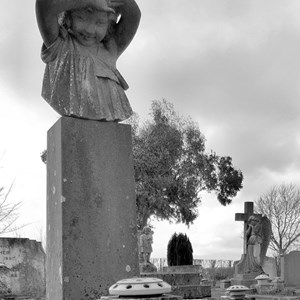 Black and white photo of headstone with young child in old section
