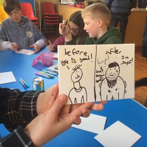 Young man showing a card he has drawn at Youth Club