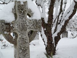 Black and white photo of cross covered in snow in old section